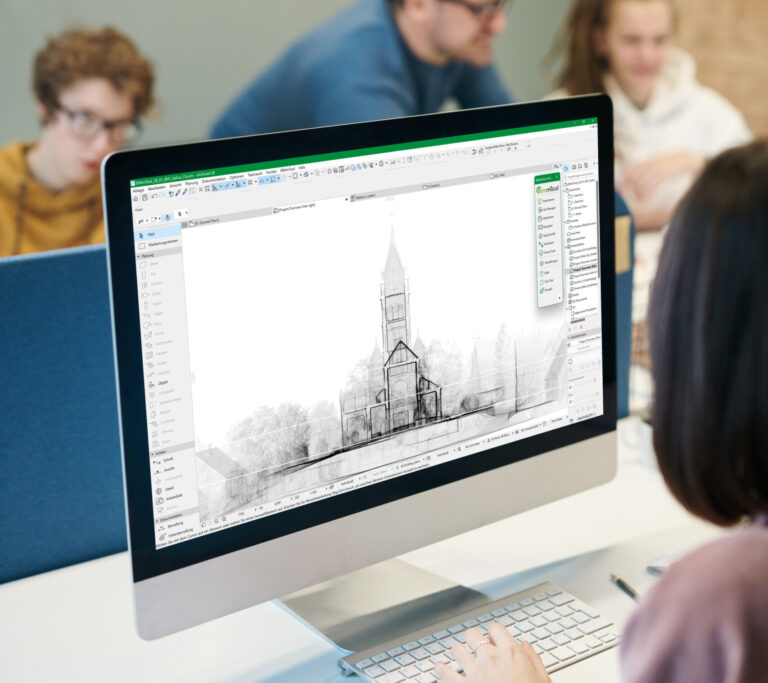Eine Person arbeitet an einem Computer, auf dem ein Gebäudeentwurf angezeigt wird. Im Hintergrund diskutieren drei Personen.